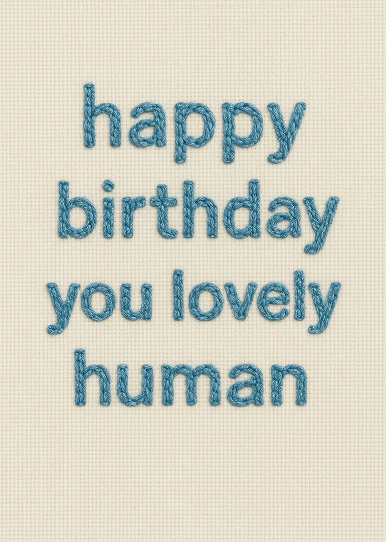 Blue embroidered happy birthday text on cream fabric for a lovely human with soft texture.
