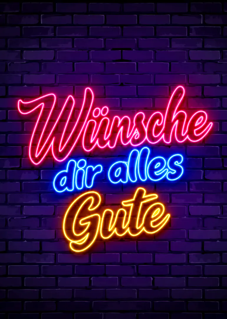 Neonschrift mit „Wünsche dir alles Gute“ in Pink, Blau und Gelb vor einer dunklen Ziegelwand.