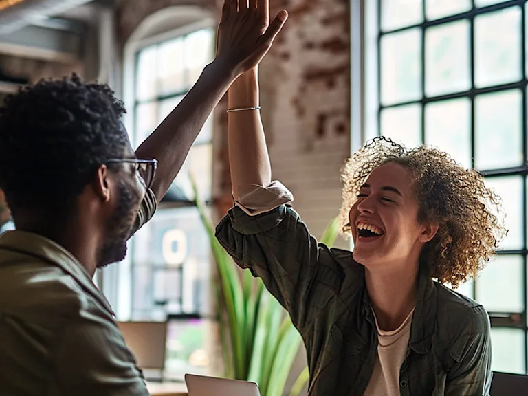 Photograph of two people high-fiving in an office setting