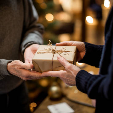 Photograph of a neatly wrapped gift being passed from one person to another