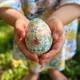 A child's hands holding a beautifully painted Easter egg, symbolizing joy and new beginnings