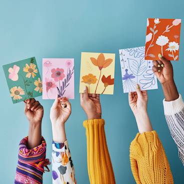 A diverse group of hands holding up colorful greeting cards