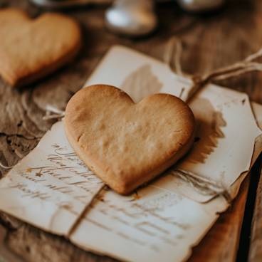 Photograph of a heart-shaped cookie nestled between Valentine's cards, symbolizing the sweet gestures that accompany our words