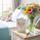 A hand-written card on a bright hospital bedside table with a vase of cheerful flowers